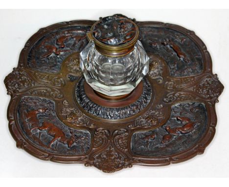 A 19th century continental bronzed pewter and brass ink stand decorated with medieval hunting scenes and brass mounted glass 