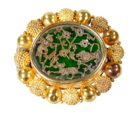 A Chinese oval brooch, with central oval design panel, with green glass backing and raised silver animal and flower motifs, i