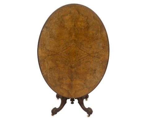 A Victorian walnut loo table, with a moulded oval quarter veneered figured tilt top,  on a carved baluster pillar and three c