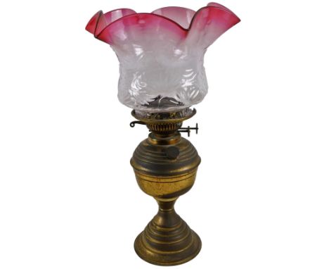 An Edwardian ruby and clear glass shade, of textured form with flared rim, 17cm H, and an early 20thC brass oil lamp.