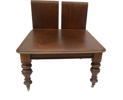 A Victorian mahogany wind out dining table, with double moulded top, and ball and stylised leaf carved inverted baluster legs