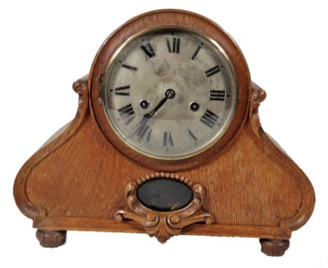 An early 20thC oak cased mantel clock, the 14cm Dia. Roman numeric dial raised above an exposed pendulum, in carved case, on 