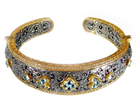 An Eastern style bangle, with tiny white CZ stone set borders, and silver pierced and scrolled design central panel, set with