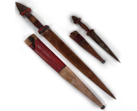 A 20thC African tribal knife and scabbard, probably Nigerian, with metal shaped end and turned handle, 56cm W, and another si