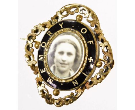 A Victorian memorial brooch, with central oval portrait, surrounded by black enamel marked In Memory Of, with outer banded de