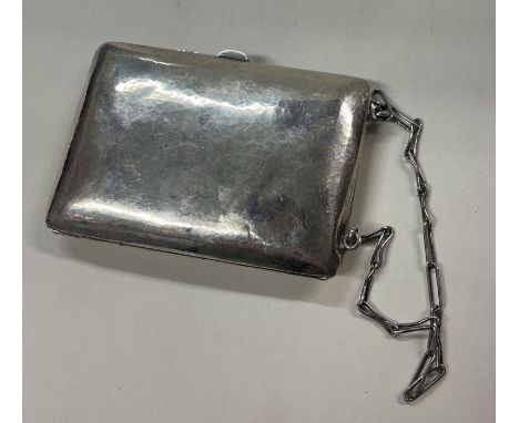 An American engraved silver bag and compact attached on a suspended chain. Approx. 98 grams. Est. £100 - £200.