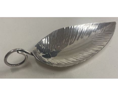 A hammered silver leaf shaped caddy spoon. Marked to base. Approx. 10 grams. Est. £40 - £60.