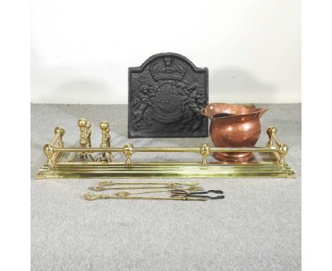 A cast iron fire back, together with a brass fender, a copper coal scuttle, fire tools and a pair of fire dogs