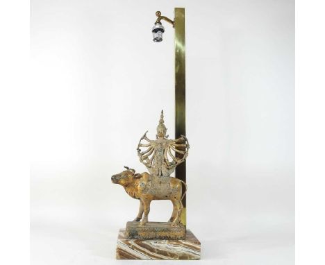 An Indian brass table lamp, mounted with a deity on a cow, on an onyx base, 69cm high