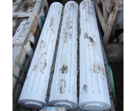 A set of three white marble architectural columns, each with fluted decoration