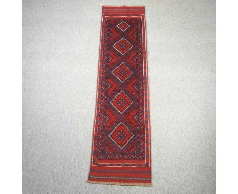 A kelim runner, with five central lozenges, on a red ground, 241 x 62cm