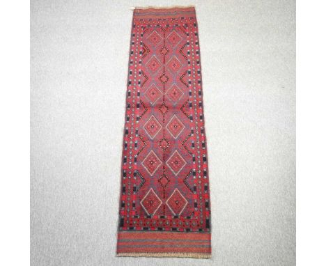 A Turkish woollen runner, with two rows of medallions, on a red ground, 244 x 63cm