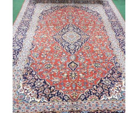 A Persian woollen carpet, having a central medallion and all over foliate designs on a red field, within multiple borders400 