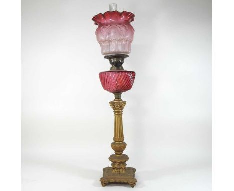 A 19th century gold painted spelter and ruby glass oil lamp, in the form of a column, with an etched clear and red frilled gl