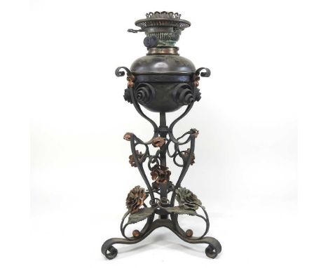 An Arts and Crafts wrought iron and copper oil lamp, of floral design, on a scrolled base, 49cm high