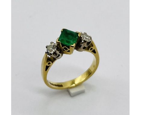 An emerald and diamond three stone ring set in 18ct gold, the central  square cut emerald measuring approx. 5mm