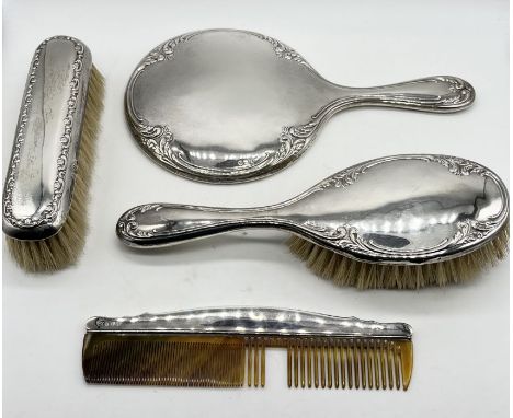 A hallmarked silver dressing table set consisting of mirror and two brushes along with a similar silver comb