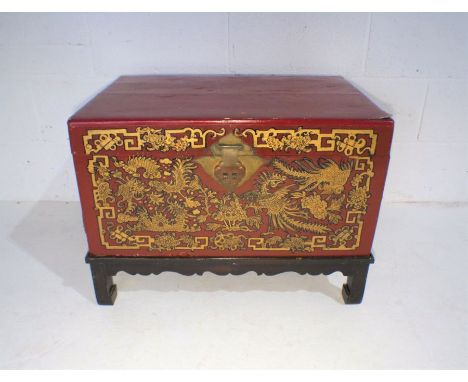 A lacquered Oriental trunk on stand with gilded decoration depicting exotic birds, fish etc - hinge A/F.