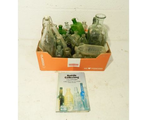 A collection of vintage glass bottles along with a book on collecting bottles