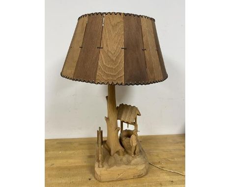 A hand carved table lamp in the form of a Man standing before a Well and Tree, base signed P.E, Caron (60cm)