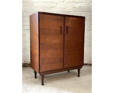 A Vintage mid century teak side cabinet by Meredew, the double doors enclosing two adjustable shelves, raised on turned suppo
