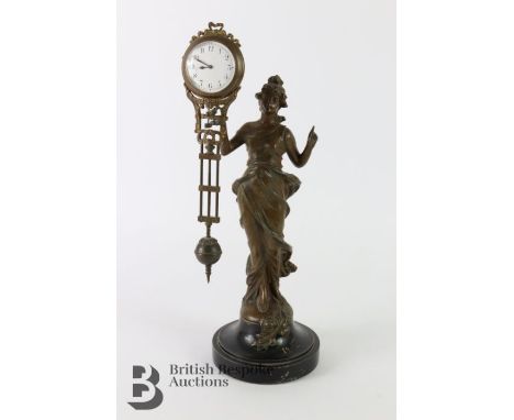 Spelter figurine, having a ball clock suspended from her extended arm, the clock having a white enamel face with Arabic dial,