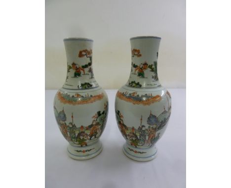 A pair of Kangxi famile verte vases decorated with figures in an idealised landscape, 28.5cm (h)
