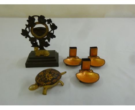 A gilt metal watch stand in the form of vine leaves on rectangular base, a brass tortoise desk bell and a three enamel on bra