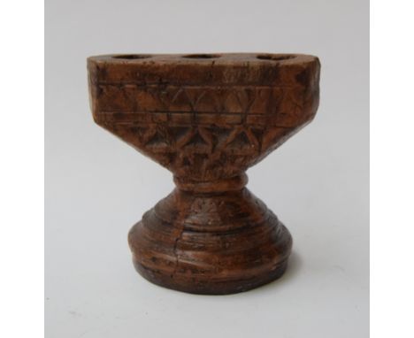 A carved wooden candlestick holder with space for three candlesticks and carved geometric pattern to the front and back