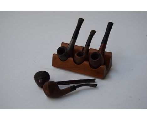 A collection of five tobacco pipes, one marked 'Carey Magic Inch', one 'Franklin', one 'Big-Ben Cadet', and a pipe stand