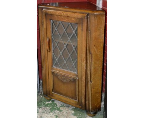 An oak Art Deco floor standing corner cabinet, glazed leaded light. 109cm high x 76cm wide x 45cm deep.