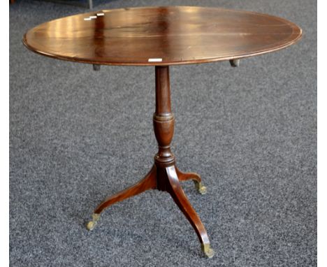 A Regency mahogany oval tilt top tripod table, crossbanded top, turned baluster column, cabriole legs, brass casters c.1810. 