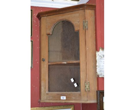 A small pine  wall mounted corner cupboard, outswept cornice, canted front, glazed door enclosing shaped shelf. 66cm high x 4