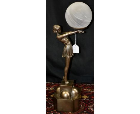 A contemporary table lamp in the form of an Art Deco girl in a gymslip holding a ball on a plinth.