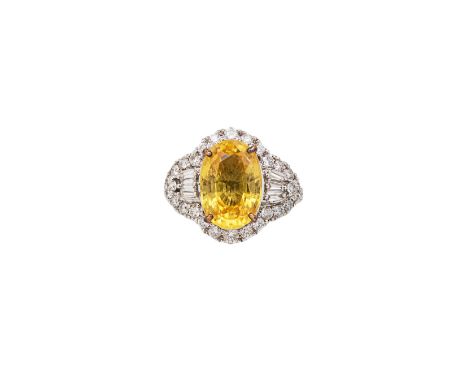 A yellow sapphire and diamond cocktail dress ring The oval shaped mixed cut yellow sapphire of good colour within an Art Deco