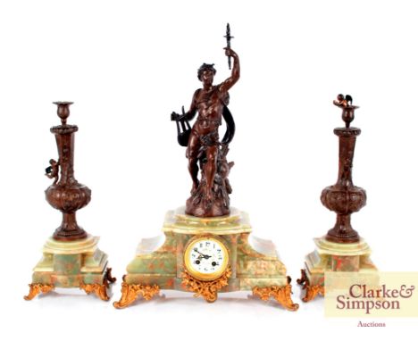 An early 20th Century green marble and spelter clock garniture, the clock surmounted by a figure and having circular floral e