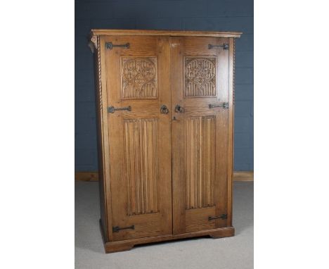 Gothic revival oak double wardrobe, with linen fold panelled doors, enclosing a single shelf and hanging rail, (in two parts)