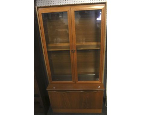 A teak display cabinet. The upper section with two panelled doors opening to reveal an adjustable teak shelf and two glass sh