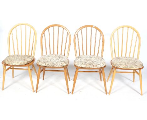 A set of four matched mid-century Ercol dining chairs with arched spindle backs. On turned tapering supports united by turned