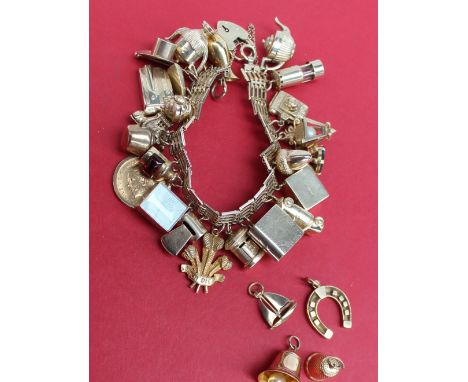 A 9ct yellow gold charm bracelet set with numerous charms including acorn, car, book, camera, miners lamp etc, approximately 