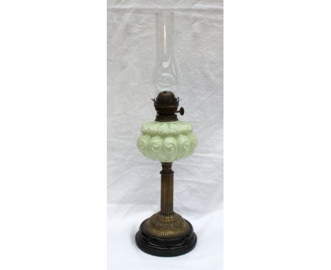 A Victorian oil lamp with a moulded opaque green glass reservoir on a reeded brass column, moulded base and circular foot