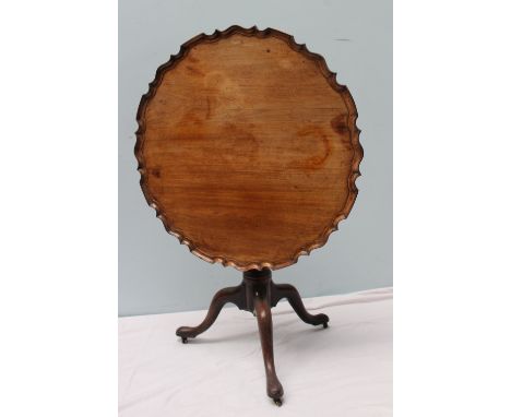 A George III mahogany tripod table, the circular top with a pie crust edge on a snap action and bird cage mechanism on a tape