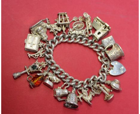 A silver charm bracelet, set with numerous charms including a candlestick telephone, lamp, Buddha etc together with a silver 