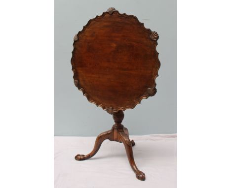 A 19th century mahogany tripod table, the circular top with a pie crust and shell border on a carved baluster column and leaf