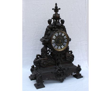 A spelter mantle clock, with a bronzed finish, the urn terminal surmount above a circular dial with Roman numerals inset, the