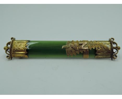 A New Zealand jade bar brooch having yellow metal decoration, no marks, tests as gold