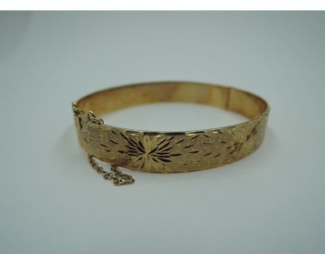 A 9ct gold hinged bangle having engraved star burst decoration and concealed clasp, approx 19.8g