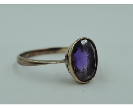 A small oval amethyst dress ring in a collared mount on a rose gold loop, marks worn tests as 9ct gold, size J &amp; 1.1g
Con