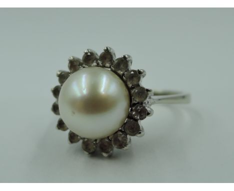 A cultured pearl and white stone cluster dress ring in claw set basket mount on a white metal loop stamped 750, size K &amp; 