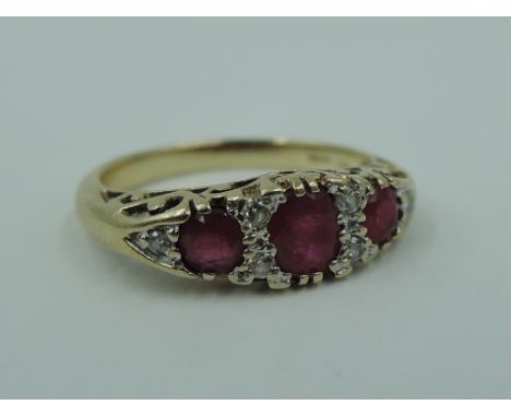 A ruby dress ring having a trio of rubies interspersed by diamond chips in a gallery mount on a 9ct gold loop, size O &amp; a